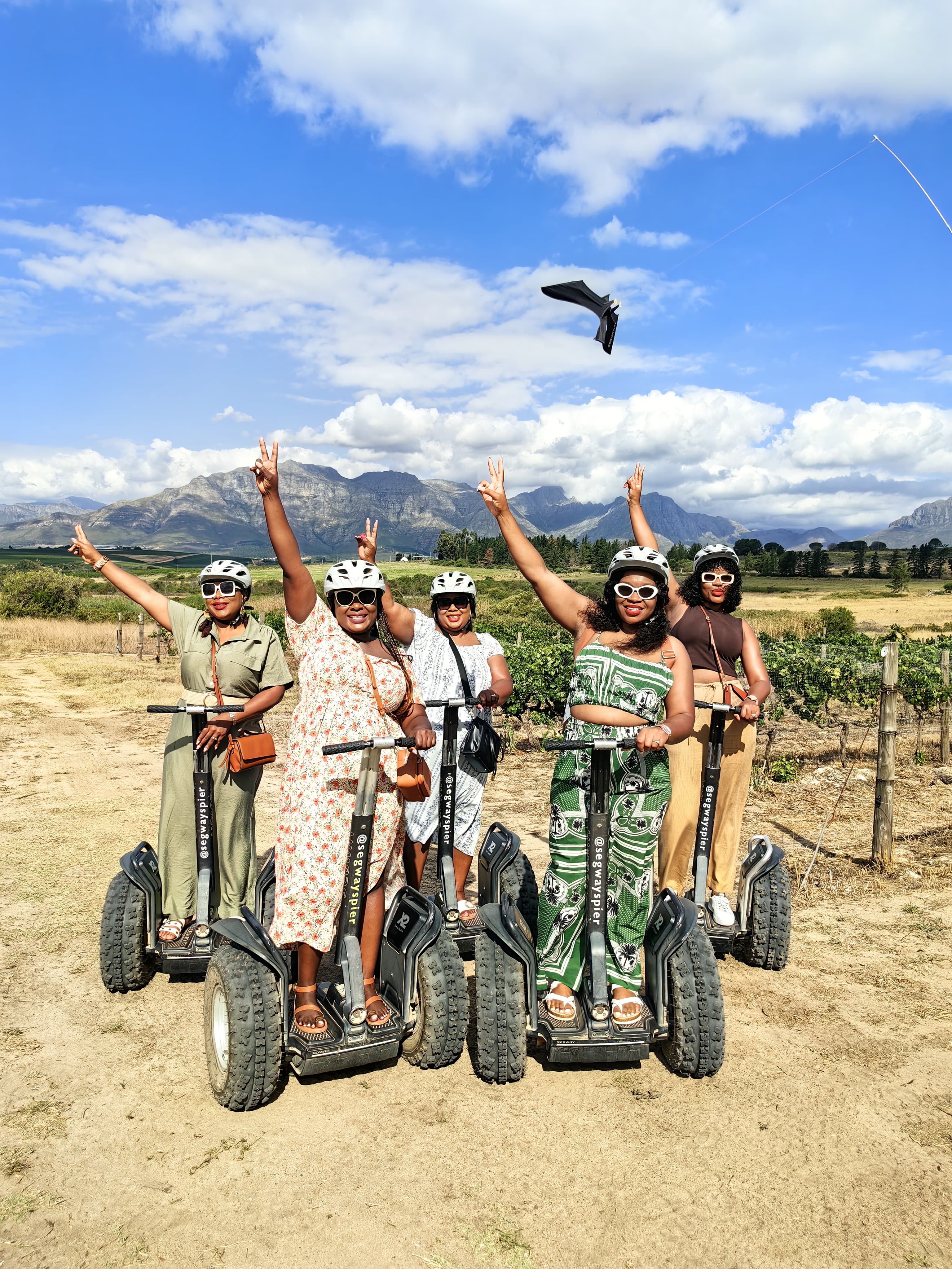 Five GSW guests celebrating on segways at a Stellenbosch wine farm with the Helderberg Mountains behind them