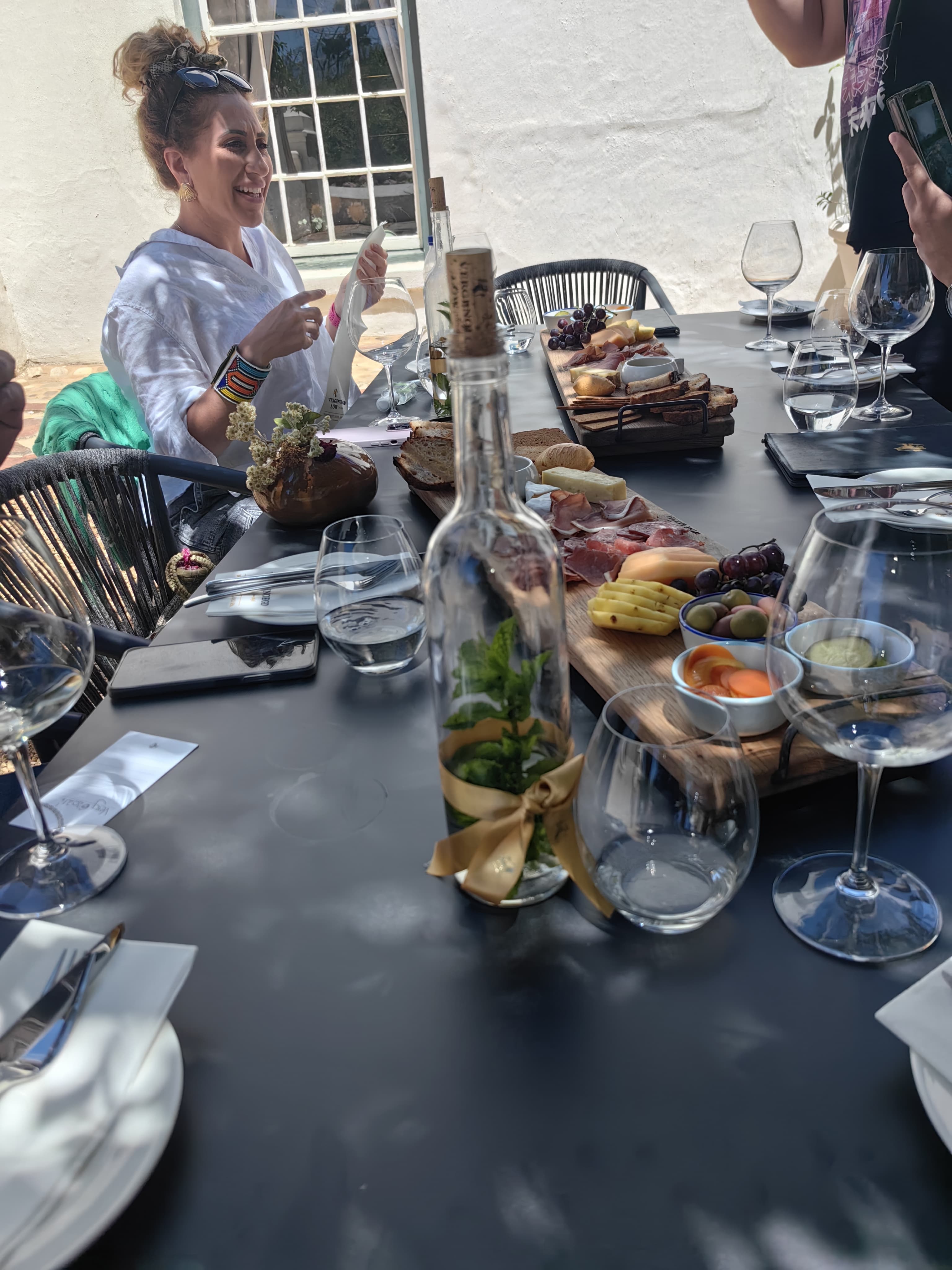 A guest laughing at a wine farm table with a charcuterie board and wine glasses