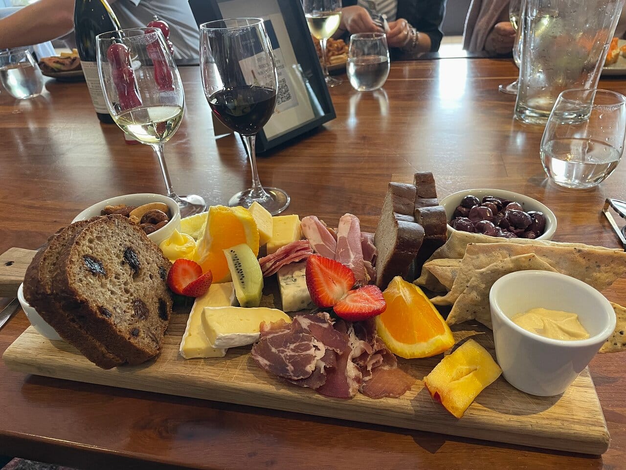 A charcuterie and cheese board with red and white wine on a Winelands table